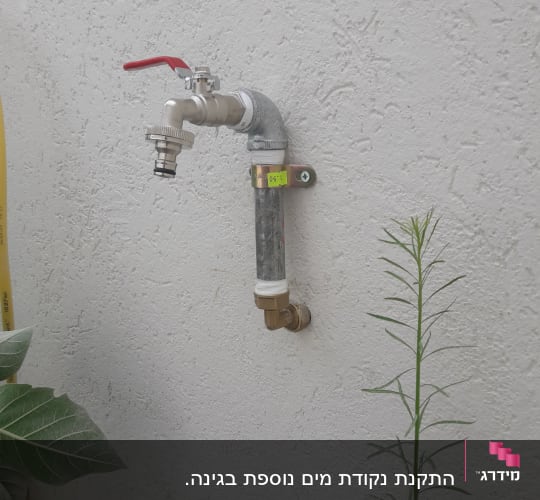 ברז מים עם ידית אדומה על קיר